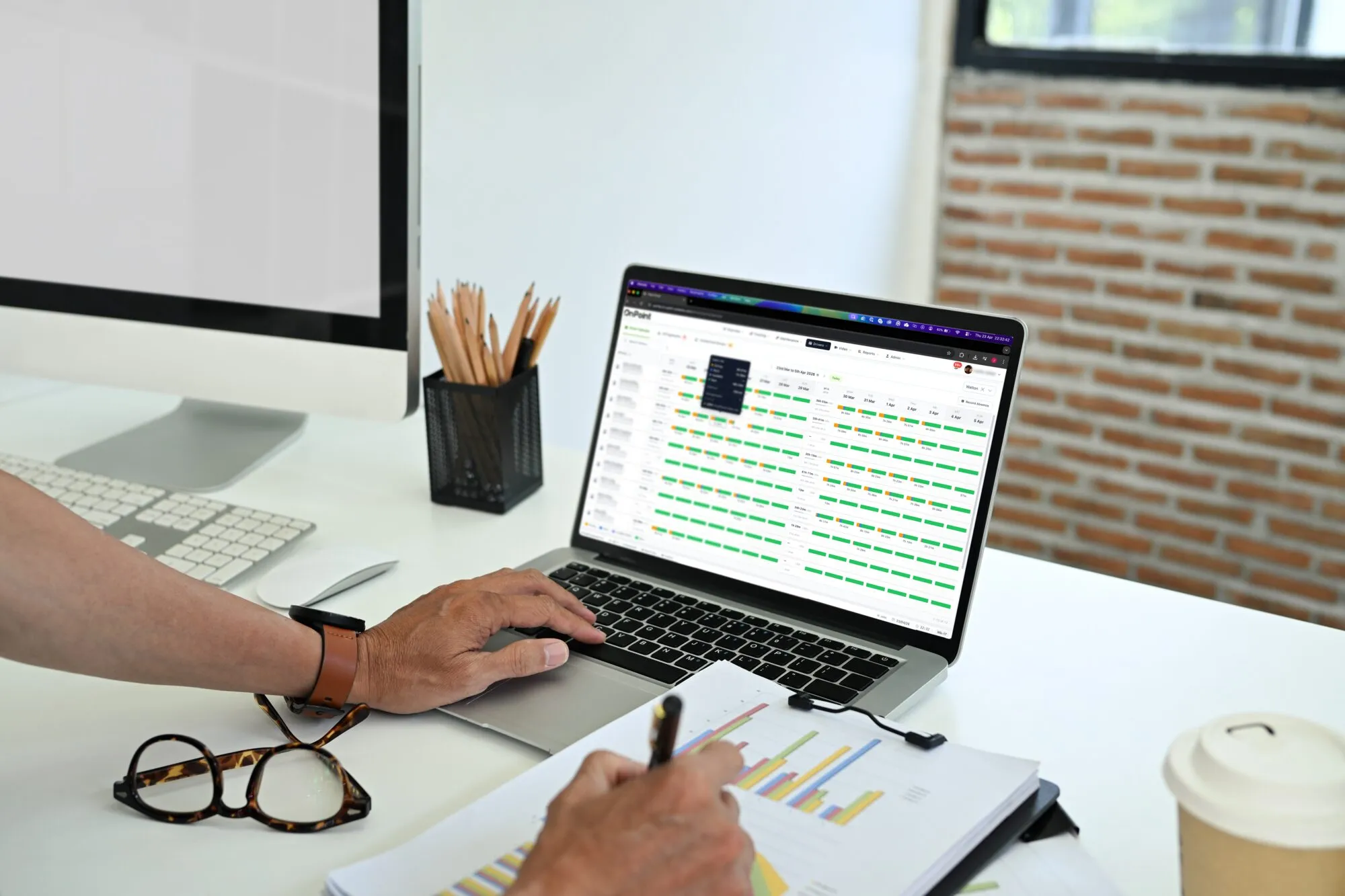 A transport manager reviewing drivers' hours timelines in the OnPoint portal on a laptop